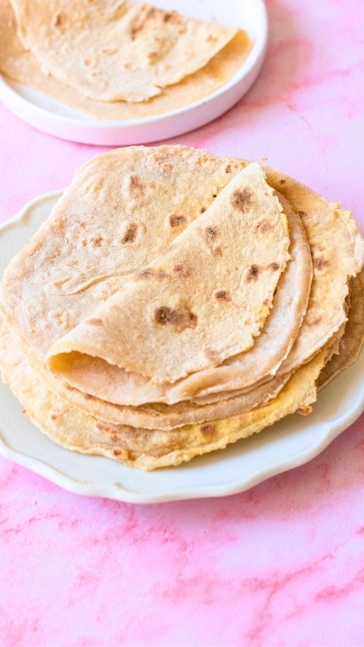 Stack of homemade flour tortillas on a plate, ready for a flour tortilla recipe.