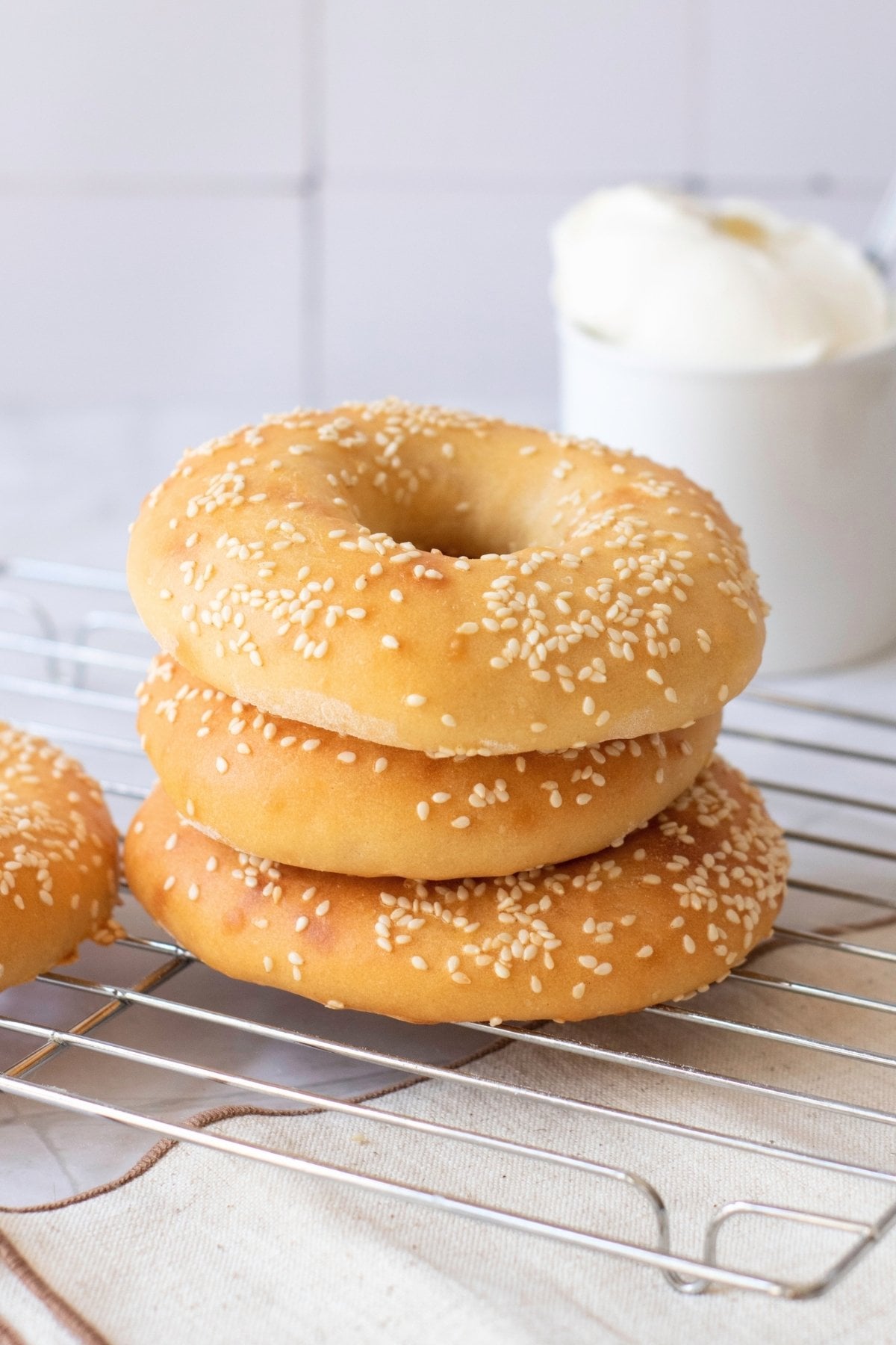 Sesame bagels on cooling rack with cream cheese.