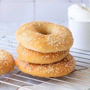 Sesame bagels stacked on cooling rack.