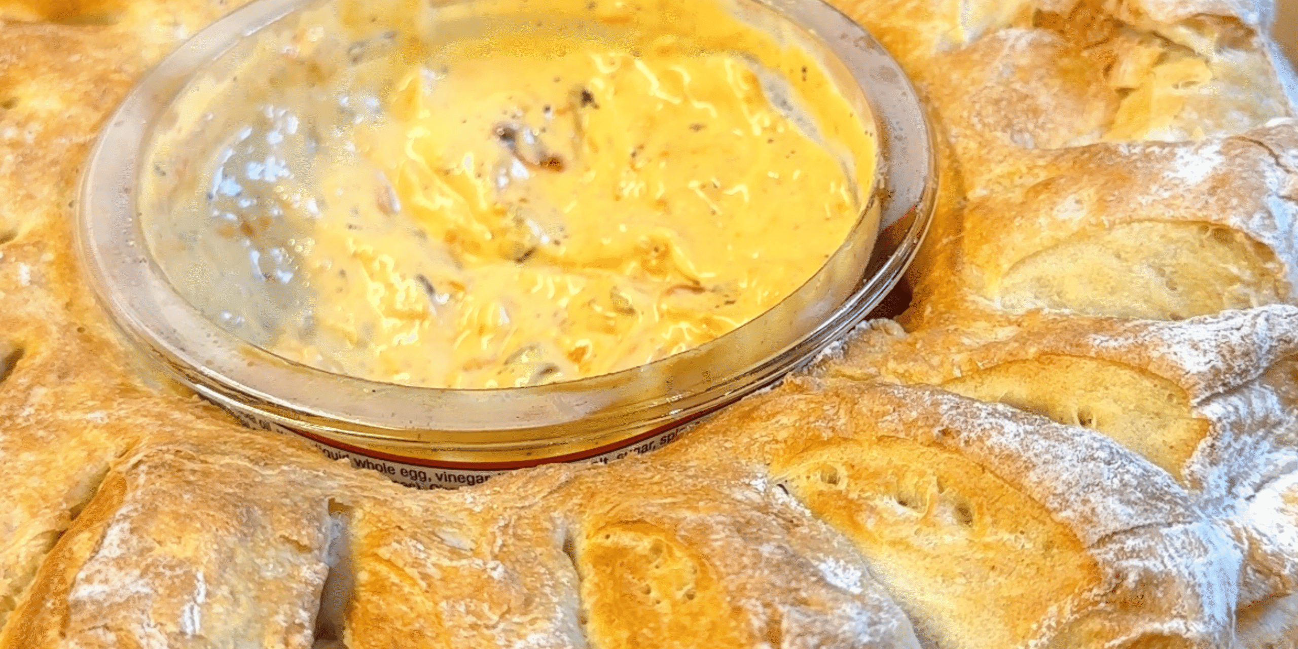 Golden bread wreath with cheese dip in the center, perfect for holidays