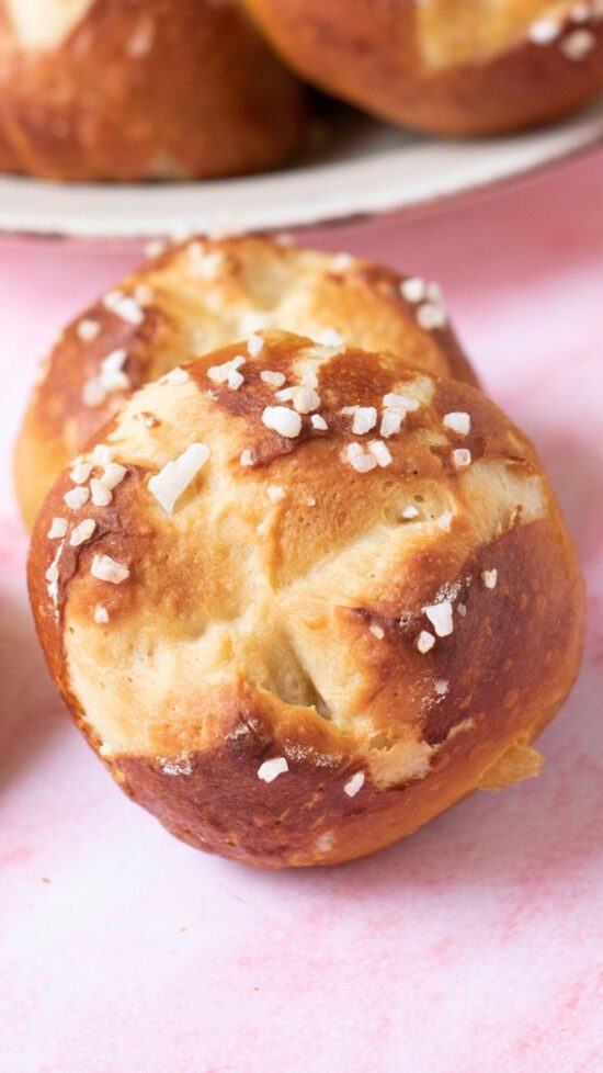 Close-up of two pretzel rolls with coarse salt, perfect for the easy pretzel roll recipe.