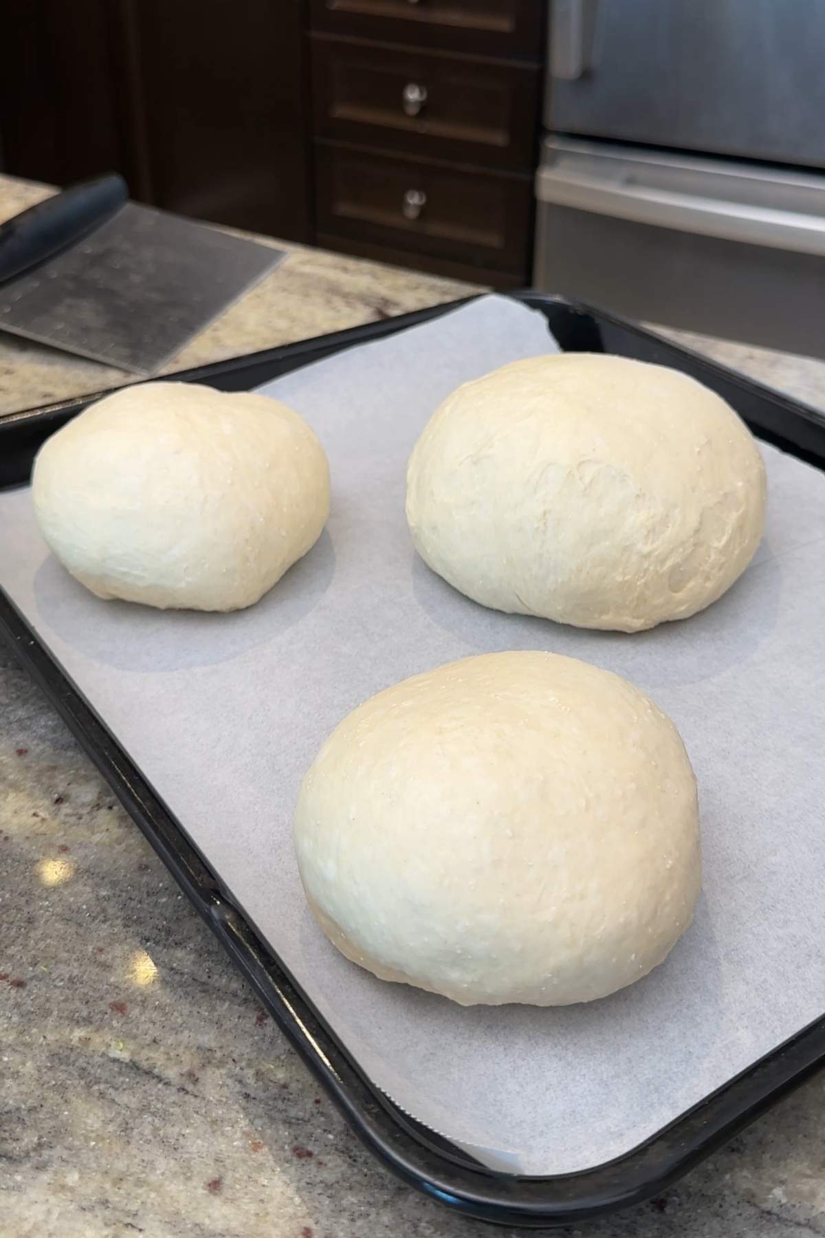 Three dough balls on baking sheet.