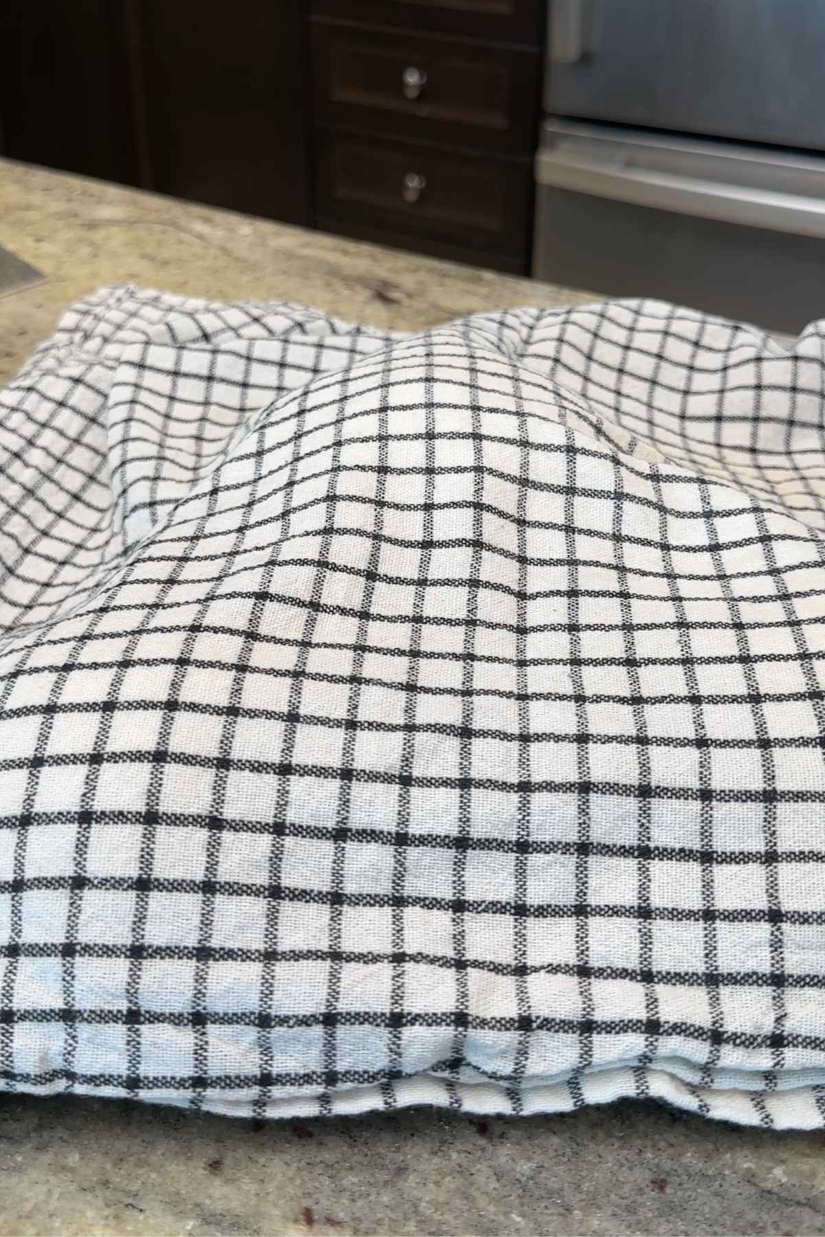 Bread dough rising under checkered cloth.