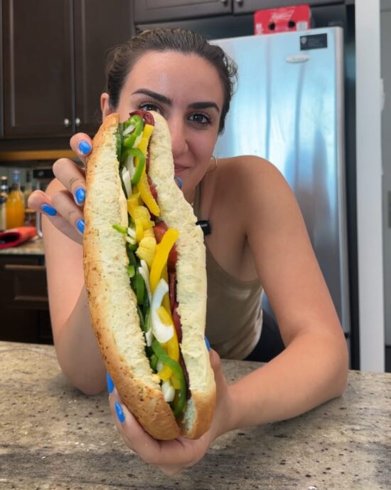 Woman holding a large Italian sub roll filled with peppers. Perfect for making Italian sub rolls!