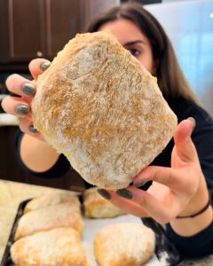 Woman holding freshly baked panini bread, part of a 5-ingredient panini bread recipe.