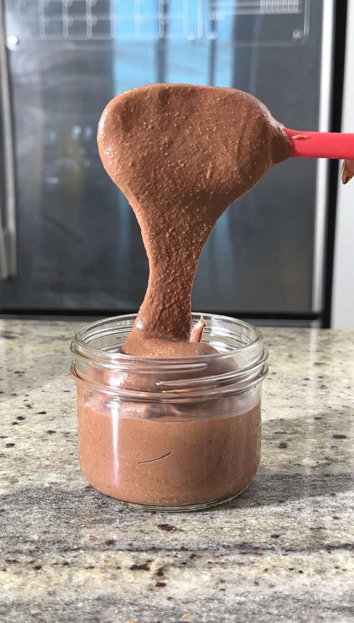 Homemade chocolate spread being poured into a jar. Nutella from scratch recipe.
