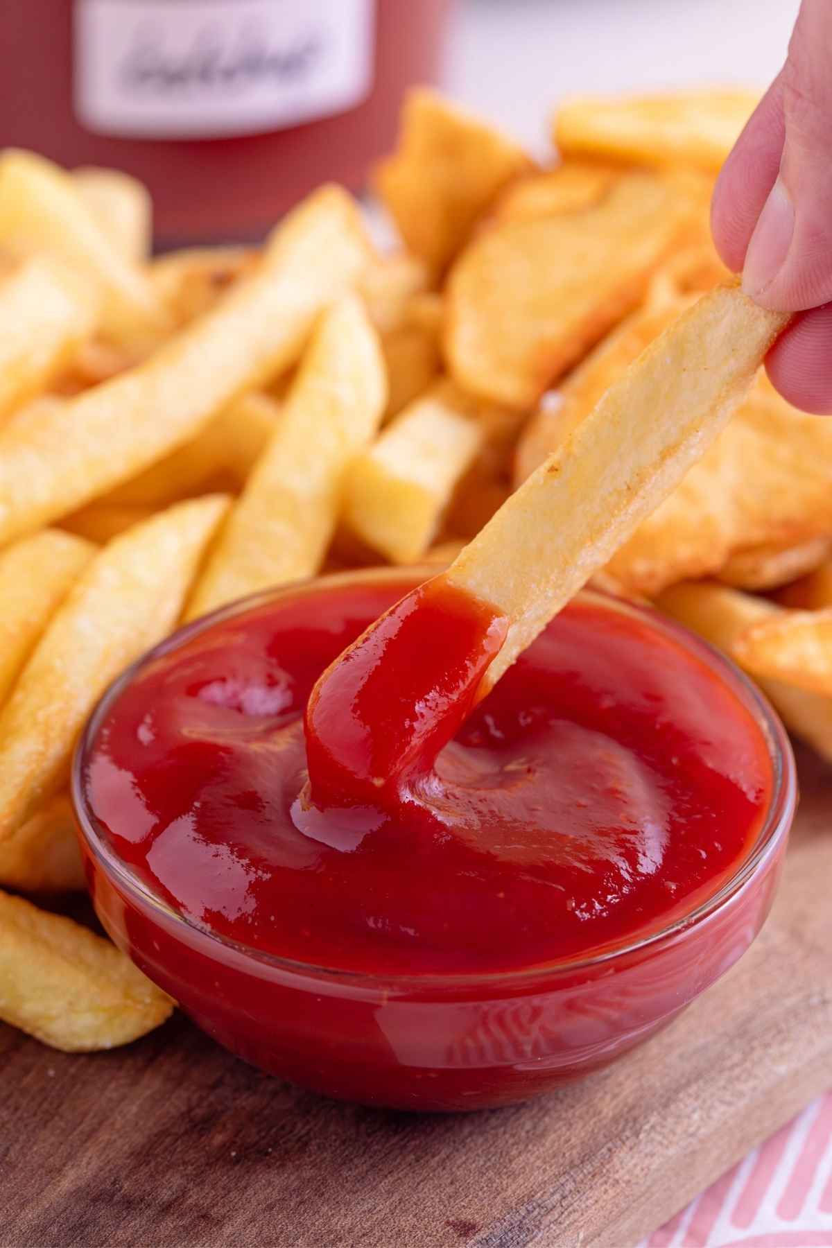 Hand dips french fry into homemade healthy ketchup.