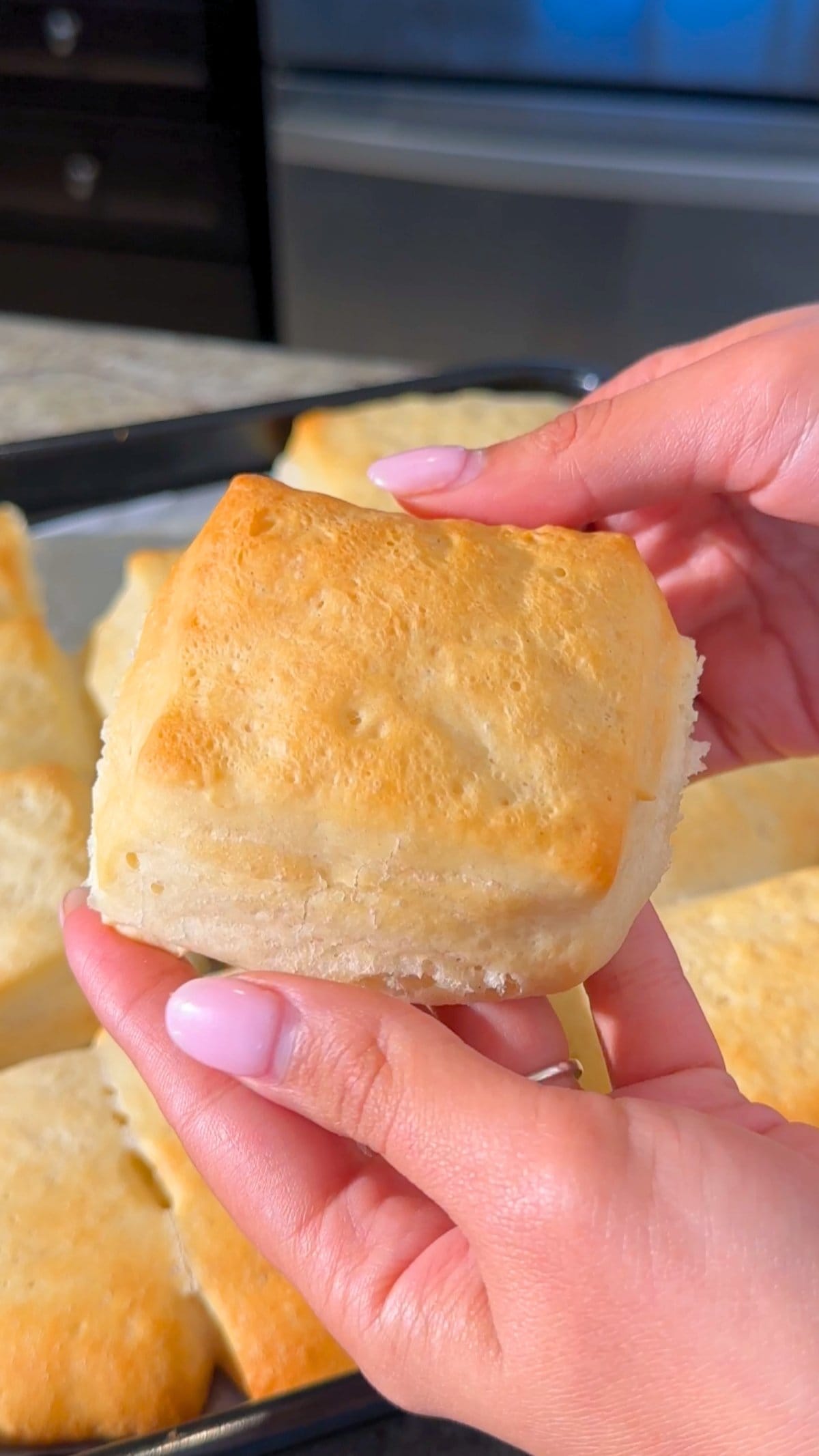 Freshly baked biscuit from a Texas Roadhouse Rolls recipe, held in hands.