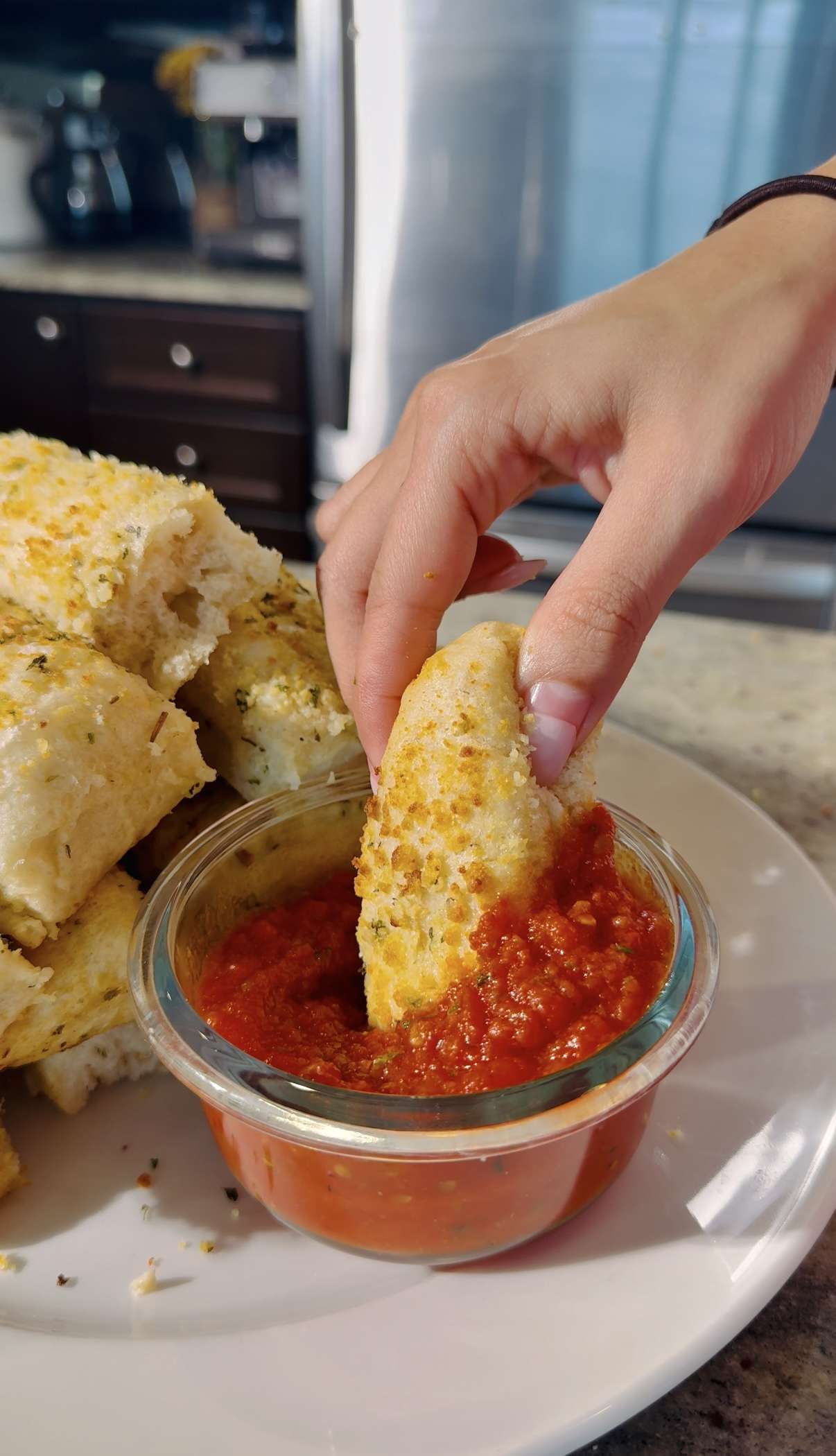 Hand dipping a Copycat Pizza Hut Garlic Parmesan Breadstick into marinara sauce. Delicious breadsticks recipe!