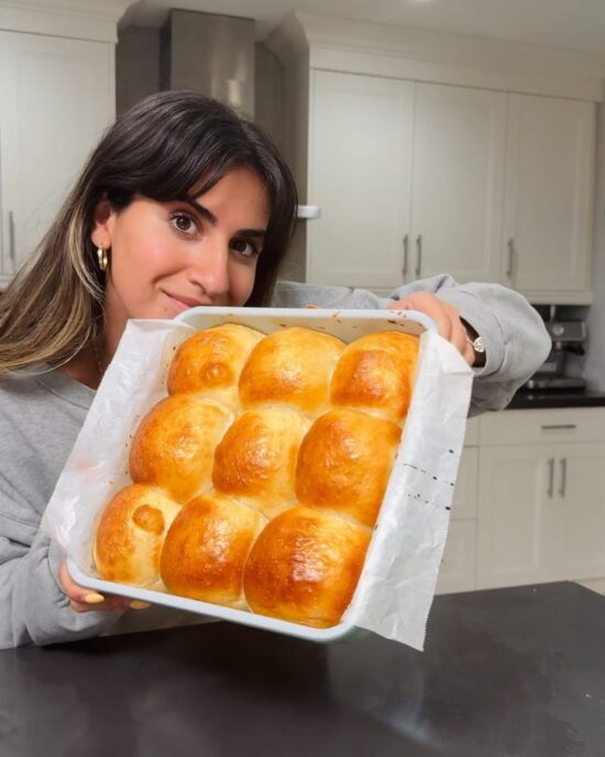 Woman holding a pan of golden Easy Dinner Rolls fresh from the oven. Delicious Easy Dinner Roll Recipe.