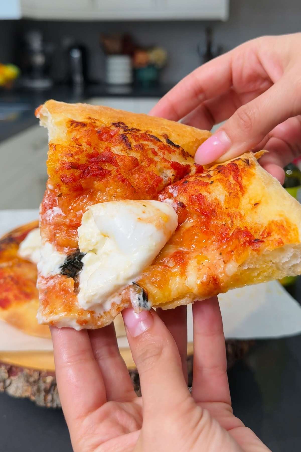 Hands holding slice of fresh Neapolitan pizza.