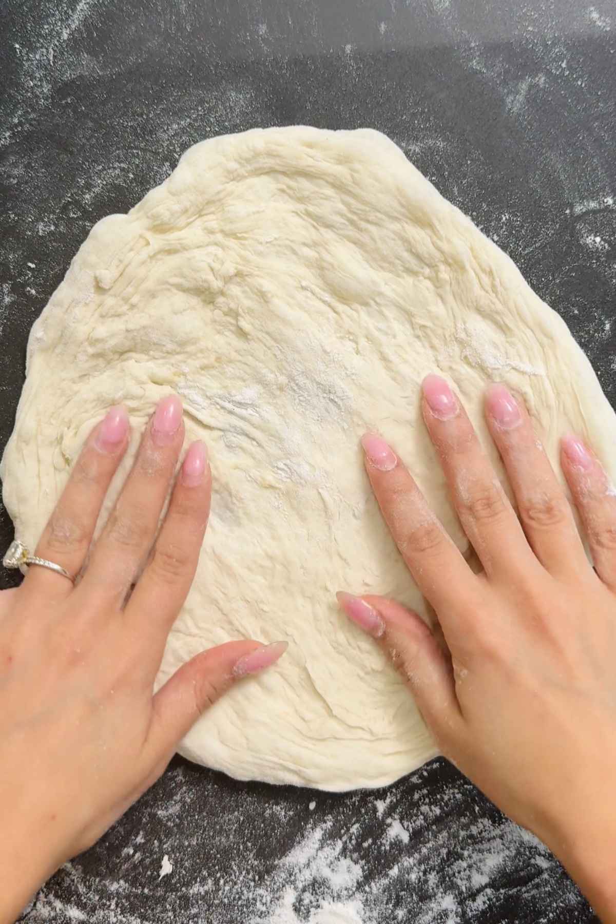 Hands shaping pizza dough.