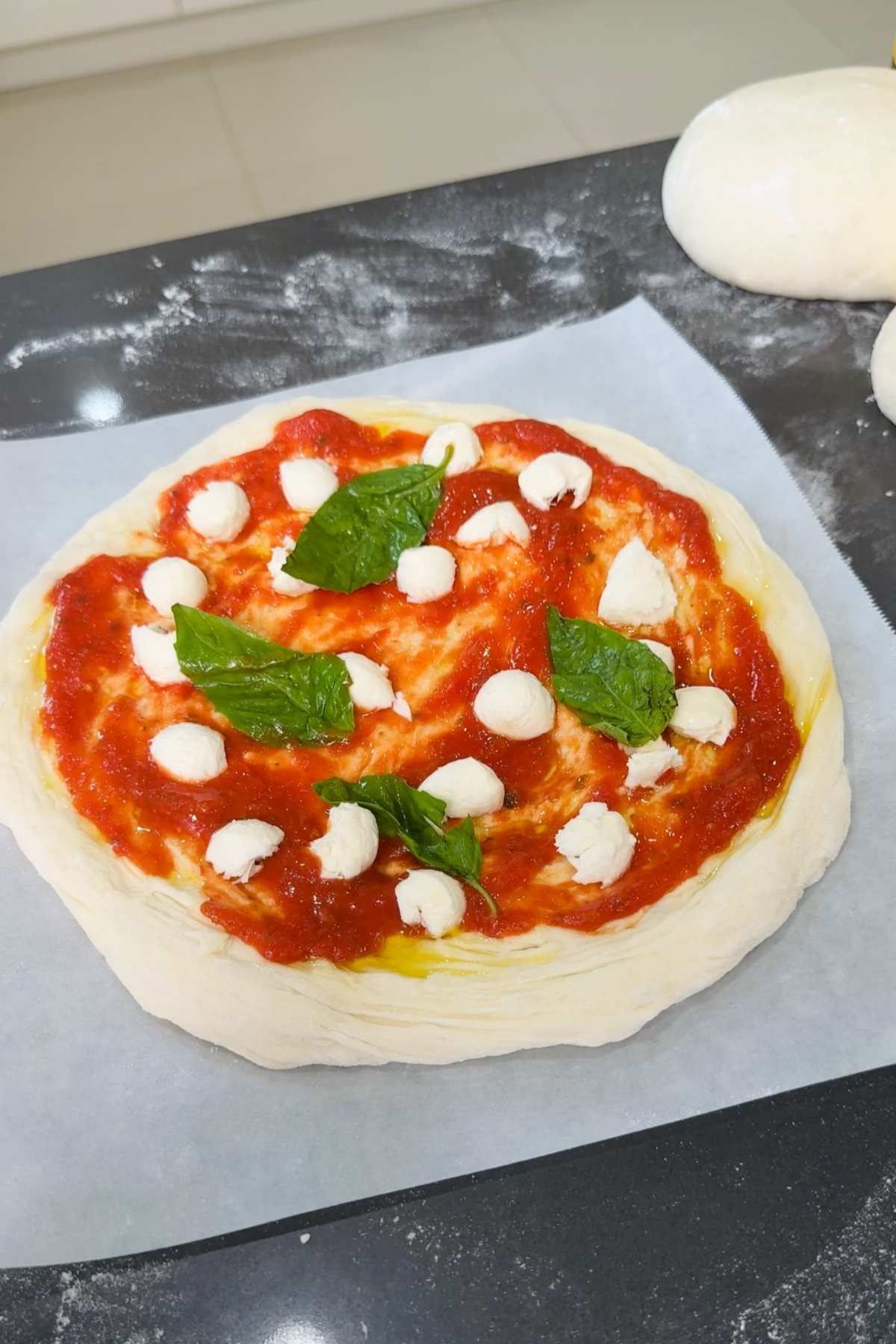 Neapolitan pizza dough with sauce, mozzarella, and basil.