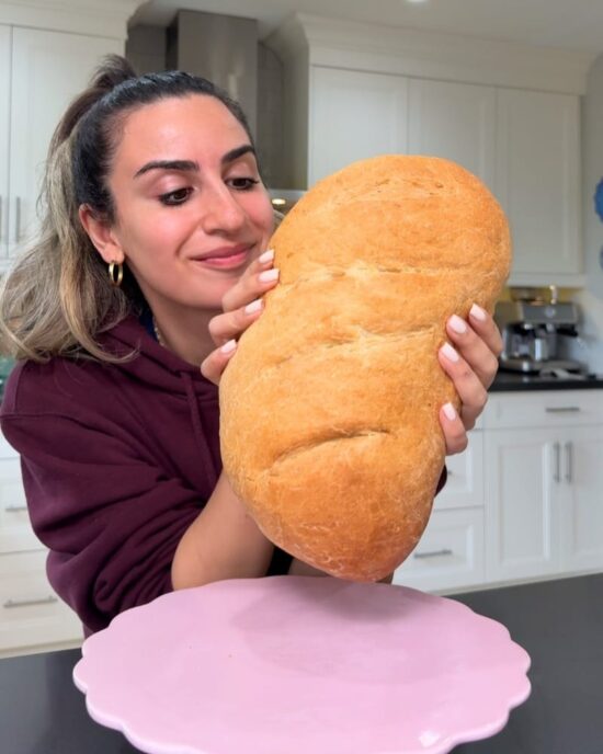 Woman holding freshly baked French bread, ready for the French bread recipe.