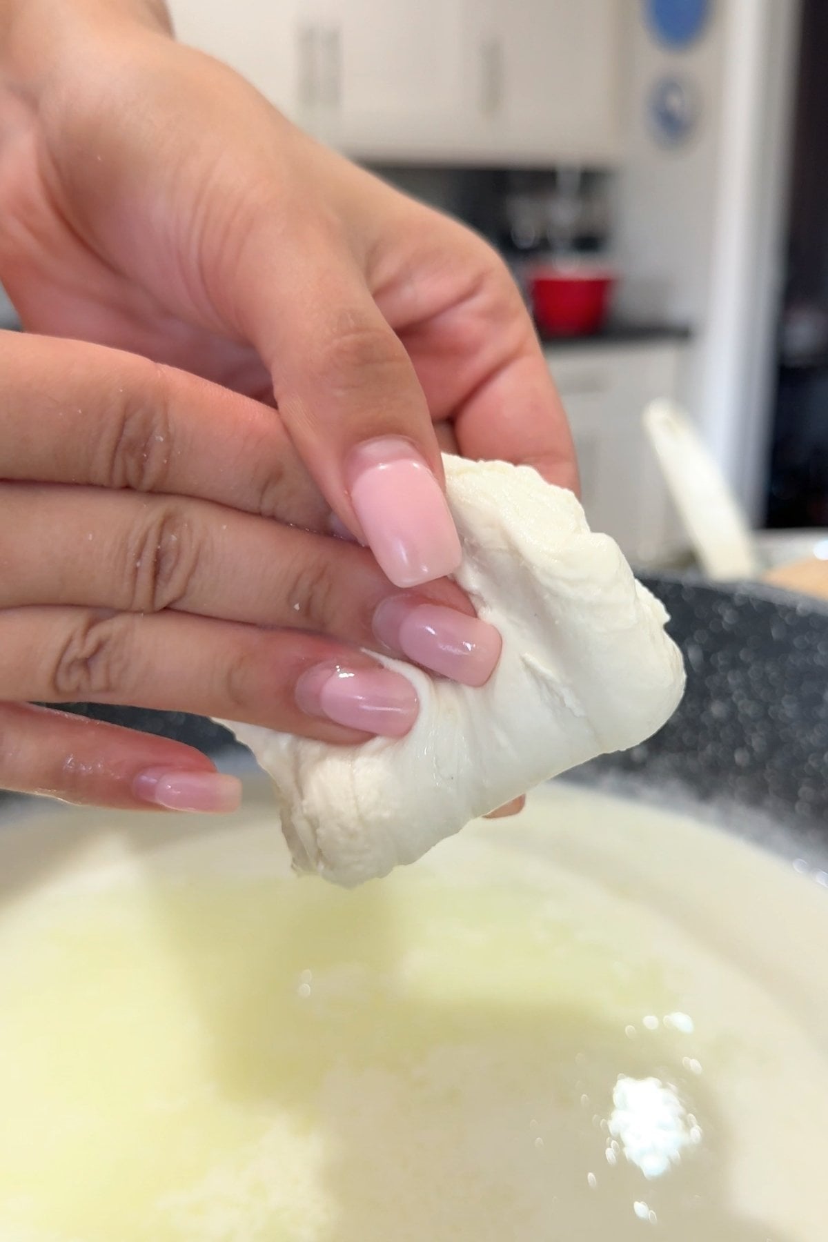 Hands kneading mozzarella in a pot