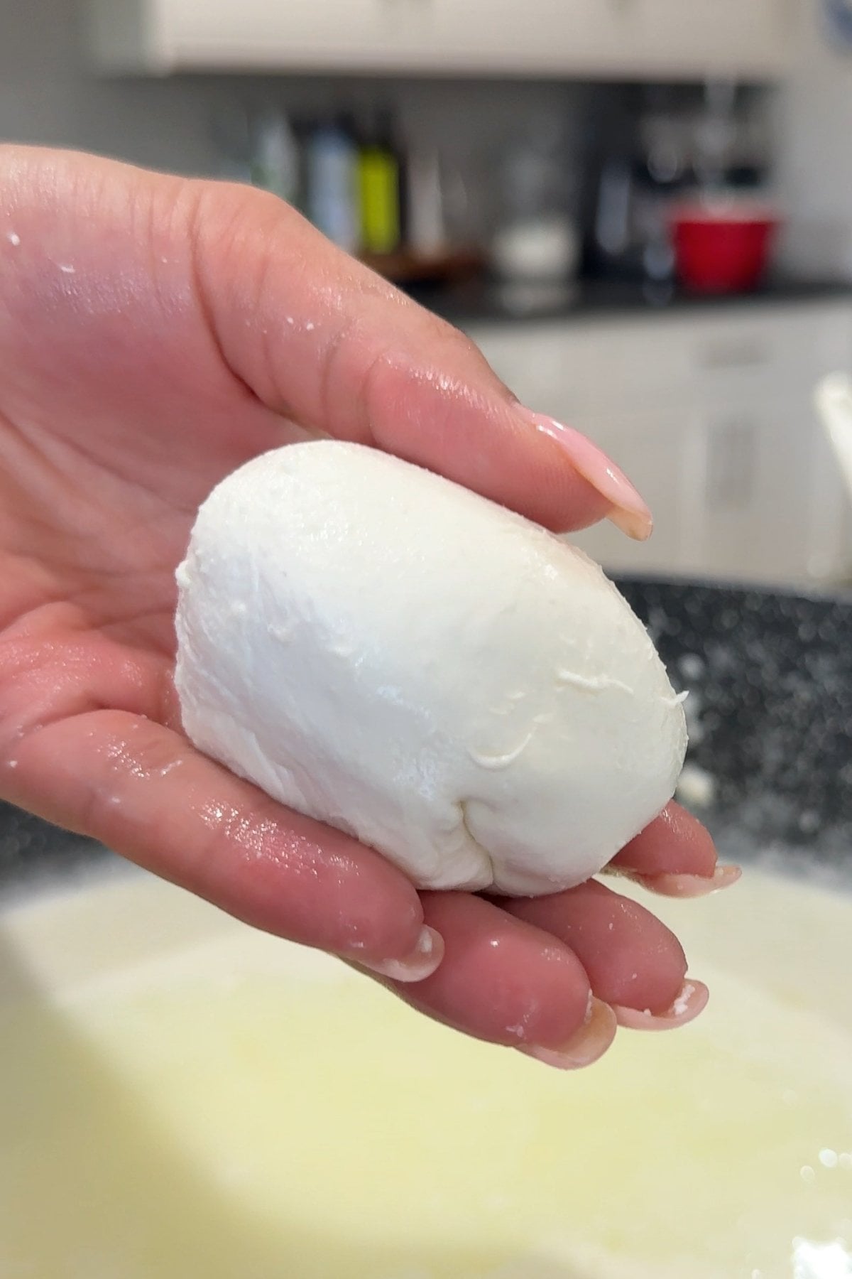 Hand holding fresh mozzarella in kitchen