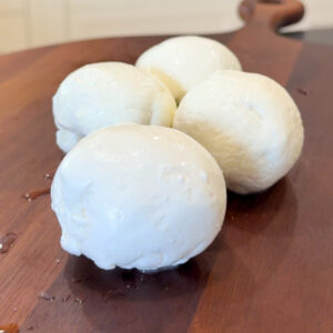 Three fresh mozzarella balls on wooden board