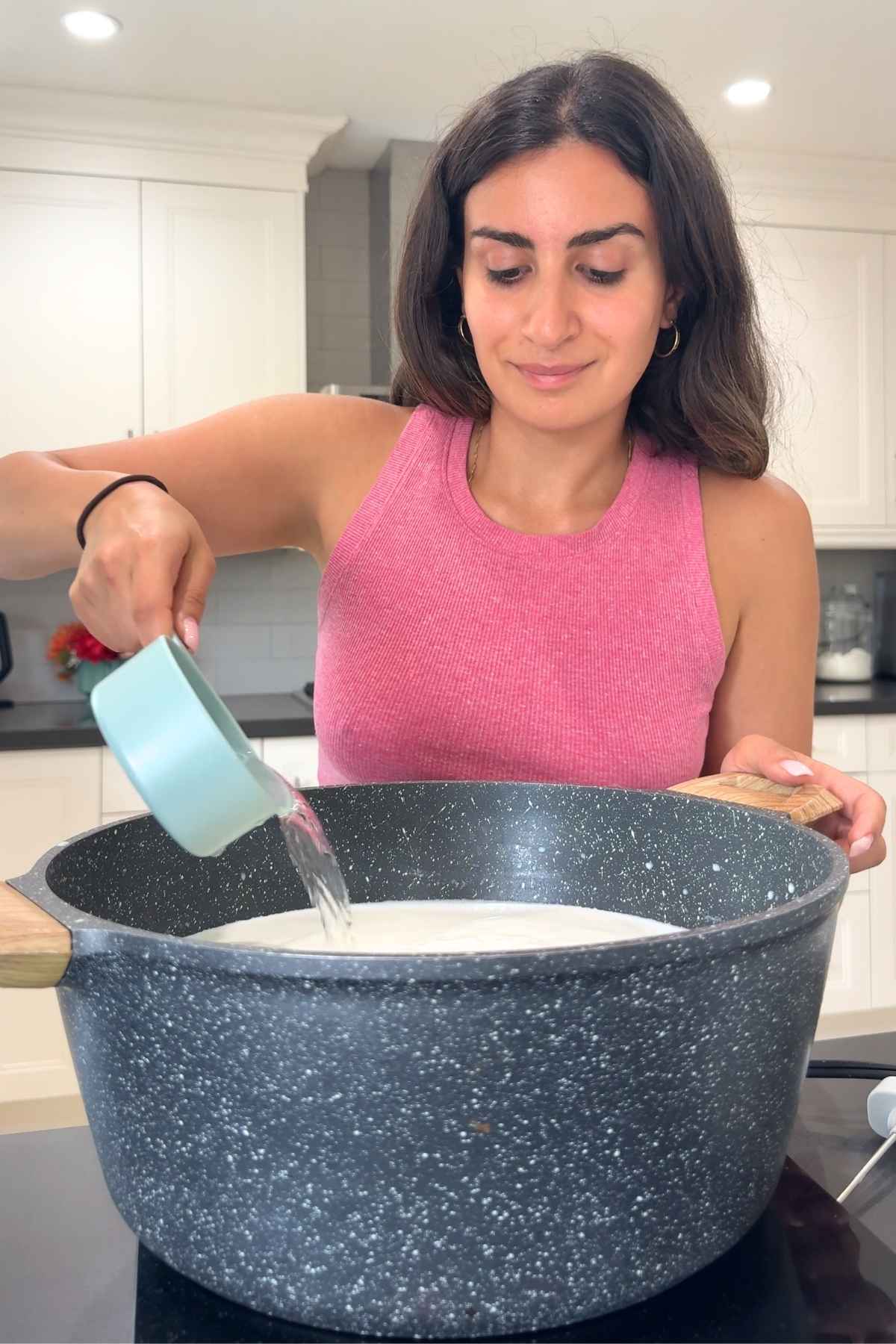 Woman pouring milk into pot for mozzarella