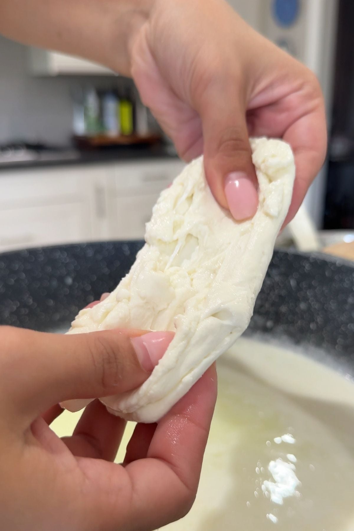 Hands holding mozzarella in a cooking pot