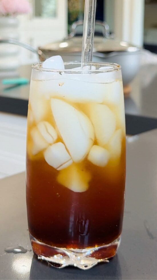 Iced drink in a glass. Homemade Coca Cola recipe drink with ice and straw.