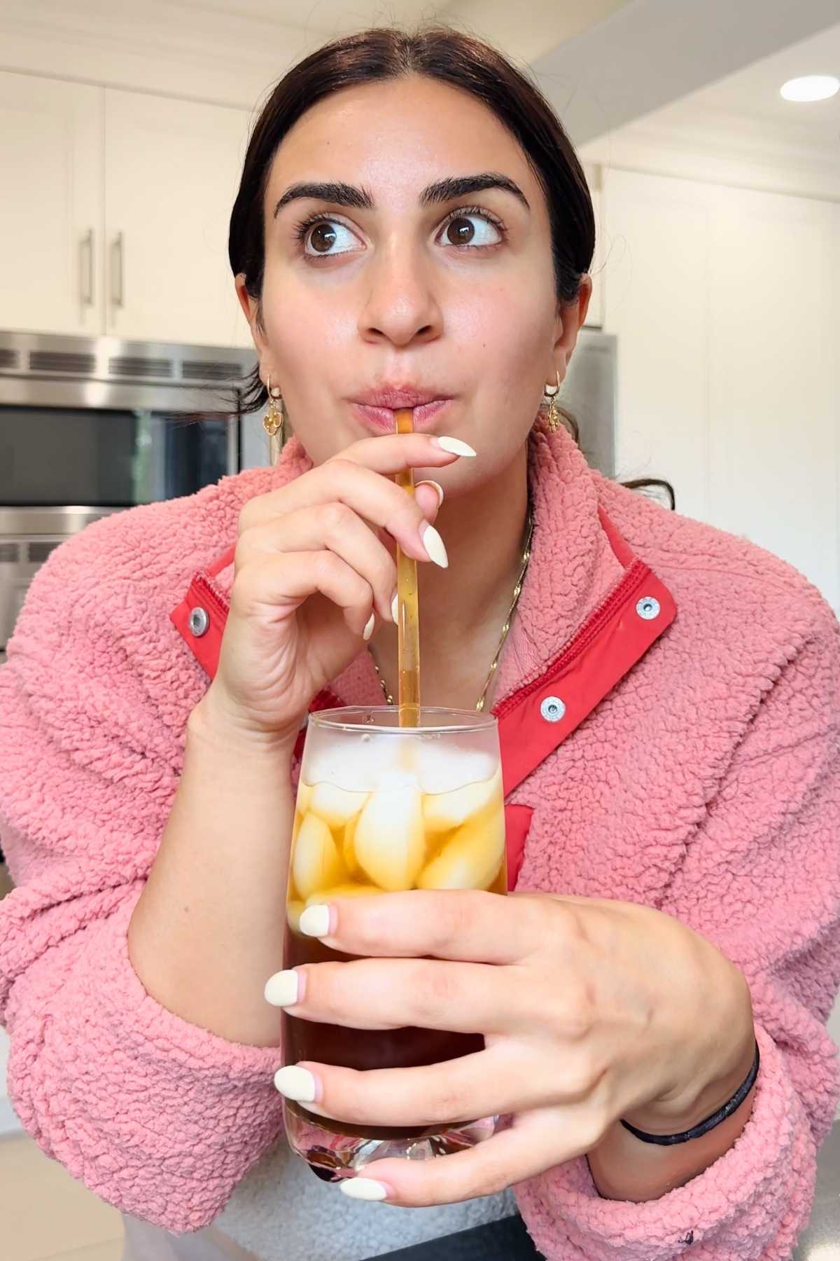 Woman drinks homemade Coca-Cola from glass.