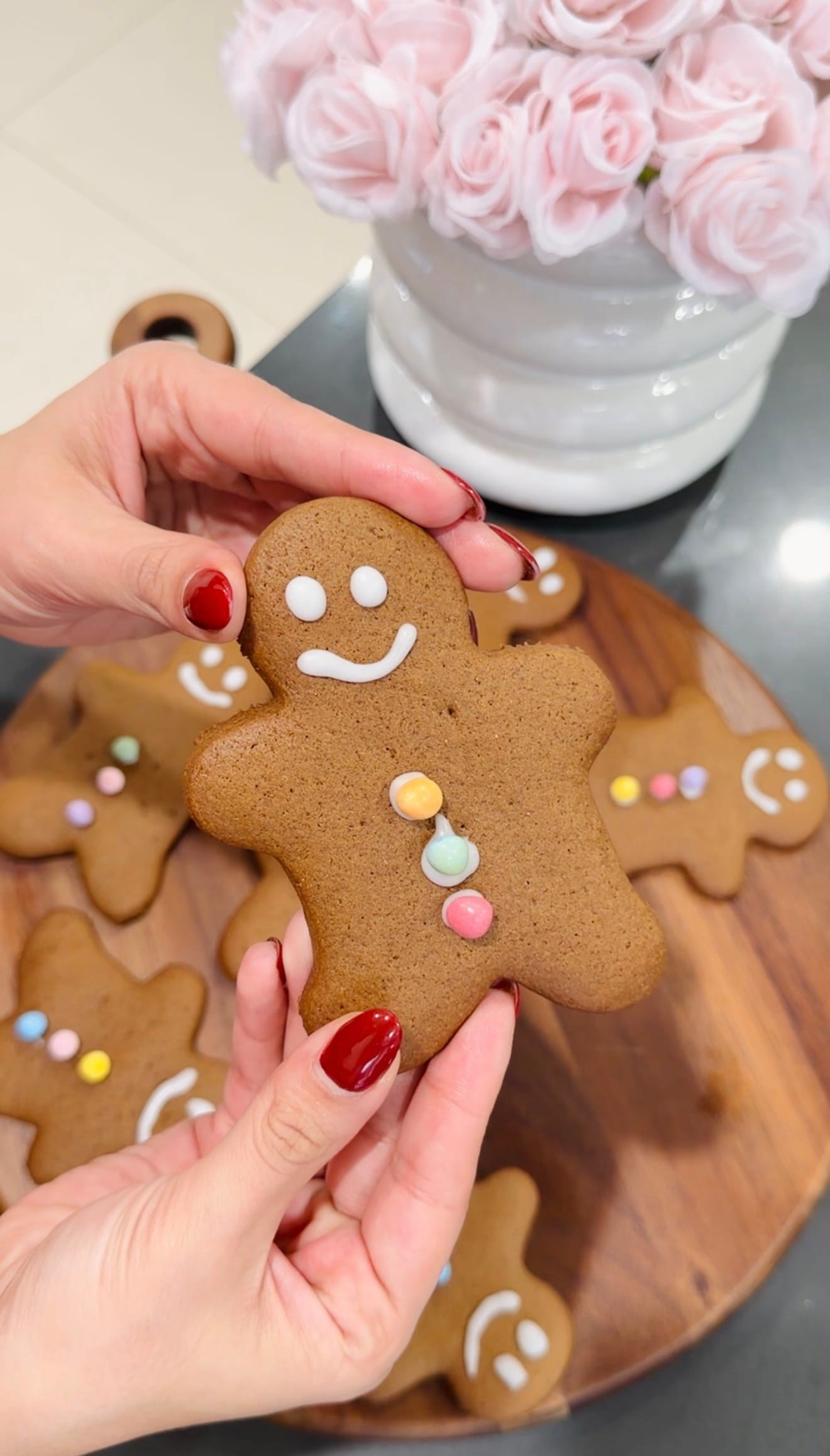 Gingerbread man cookie held up, decorated with white icing and colorful candy buttons. Easy gingerbread cookie recipe.