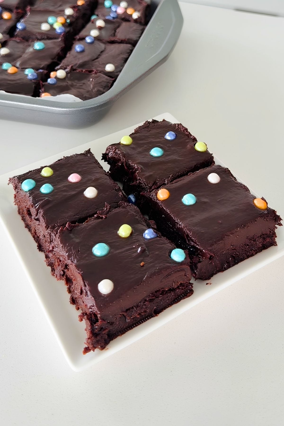 Chocolate brownies with colorful sprinkles on a white plate.