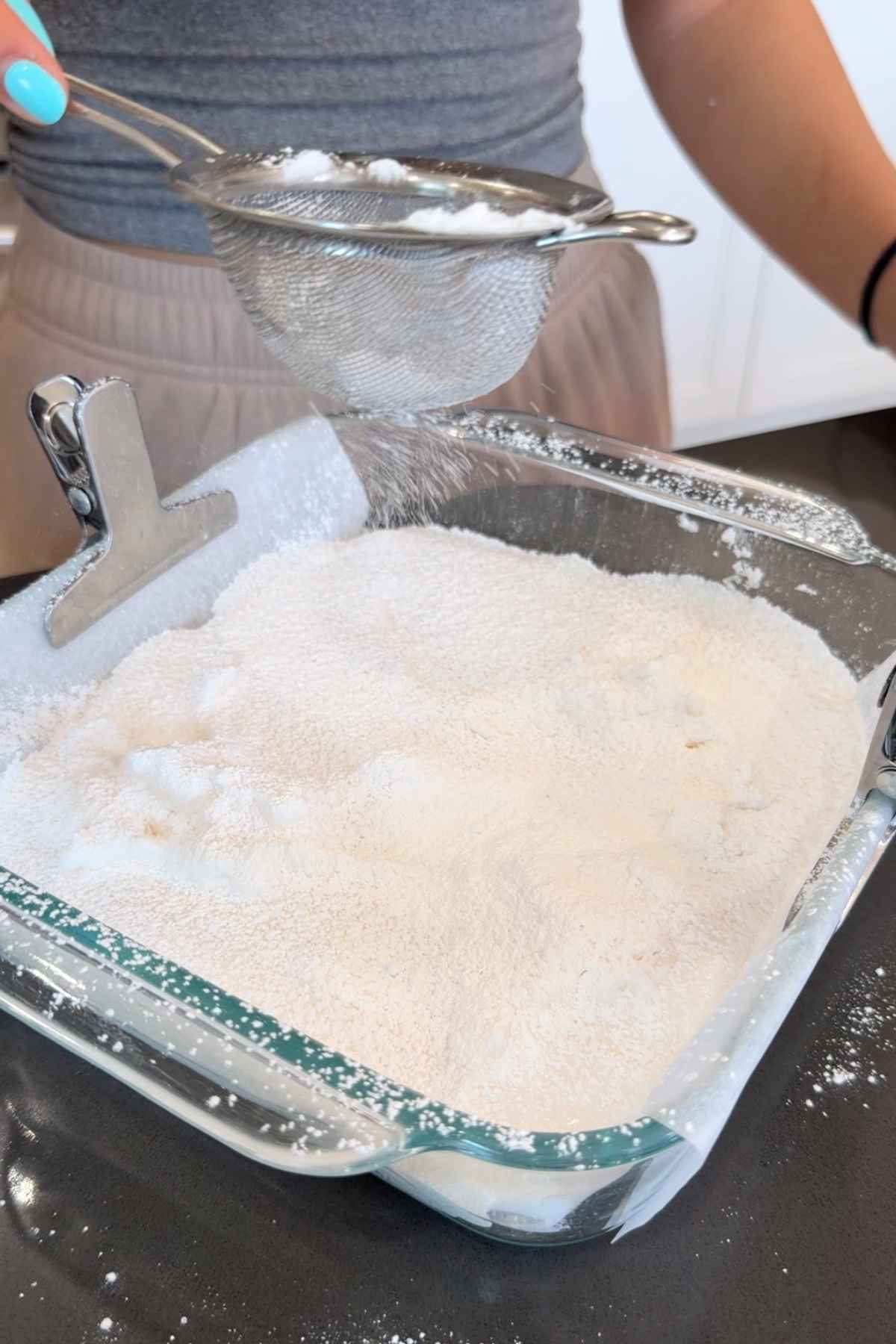 Sifting powdered sugar onto marshmallows.