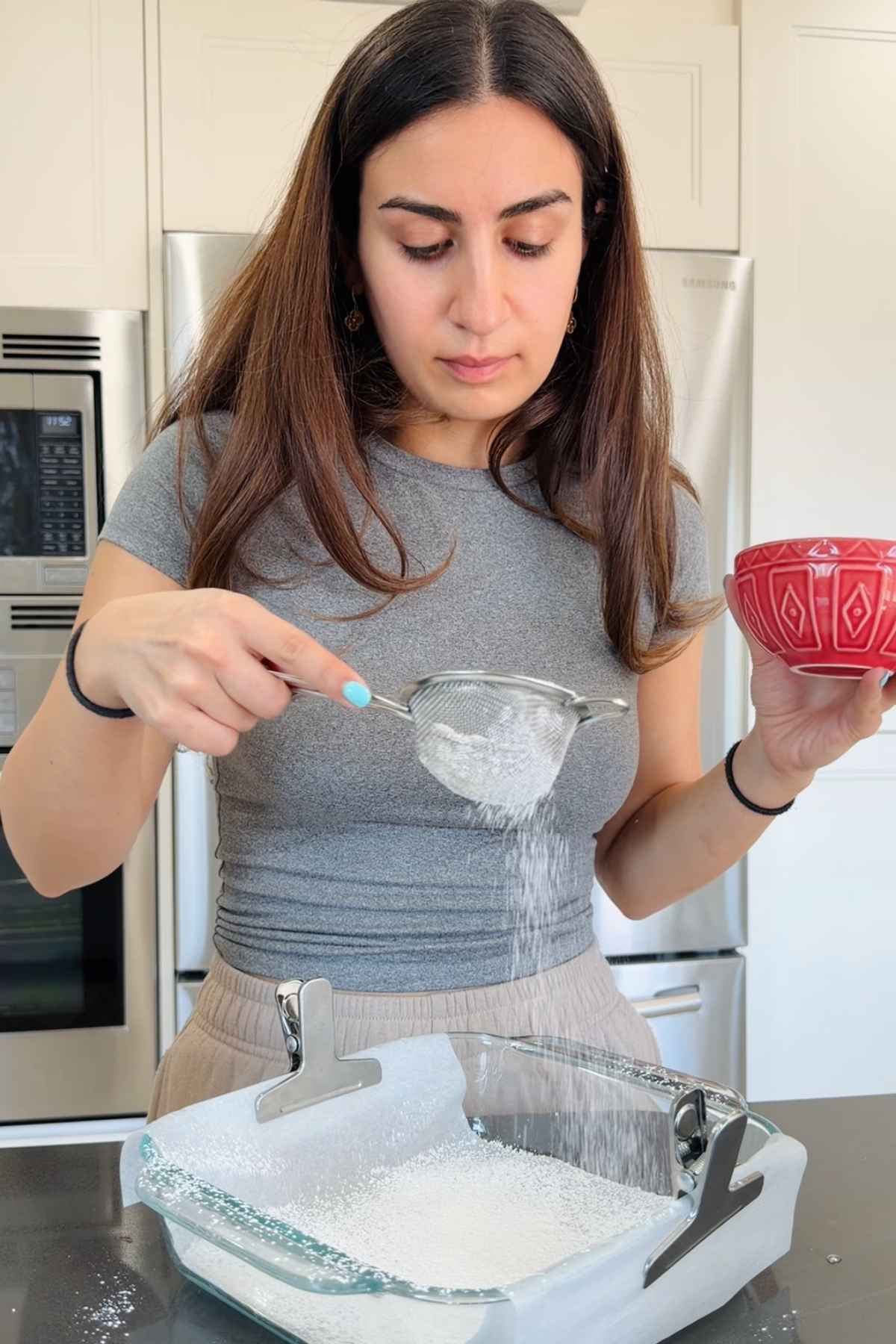Woman sifting powdered sugar onto marshmallows.