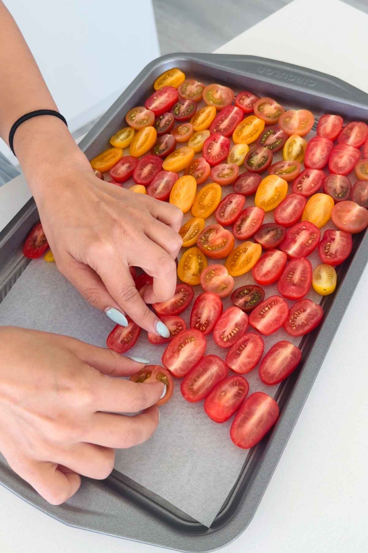 Halved cherry tomatoes arranged on baking sheet.