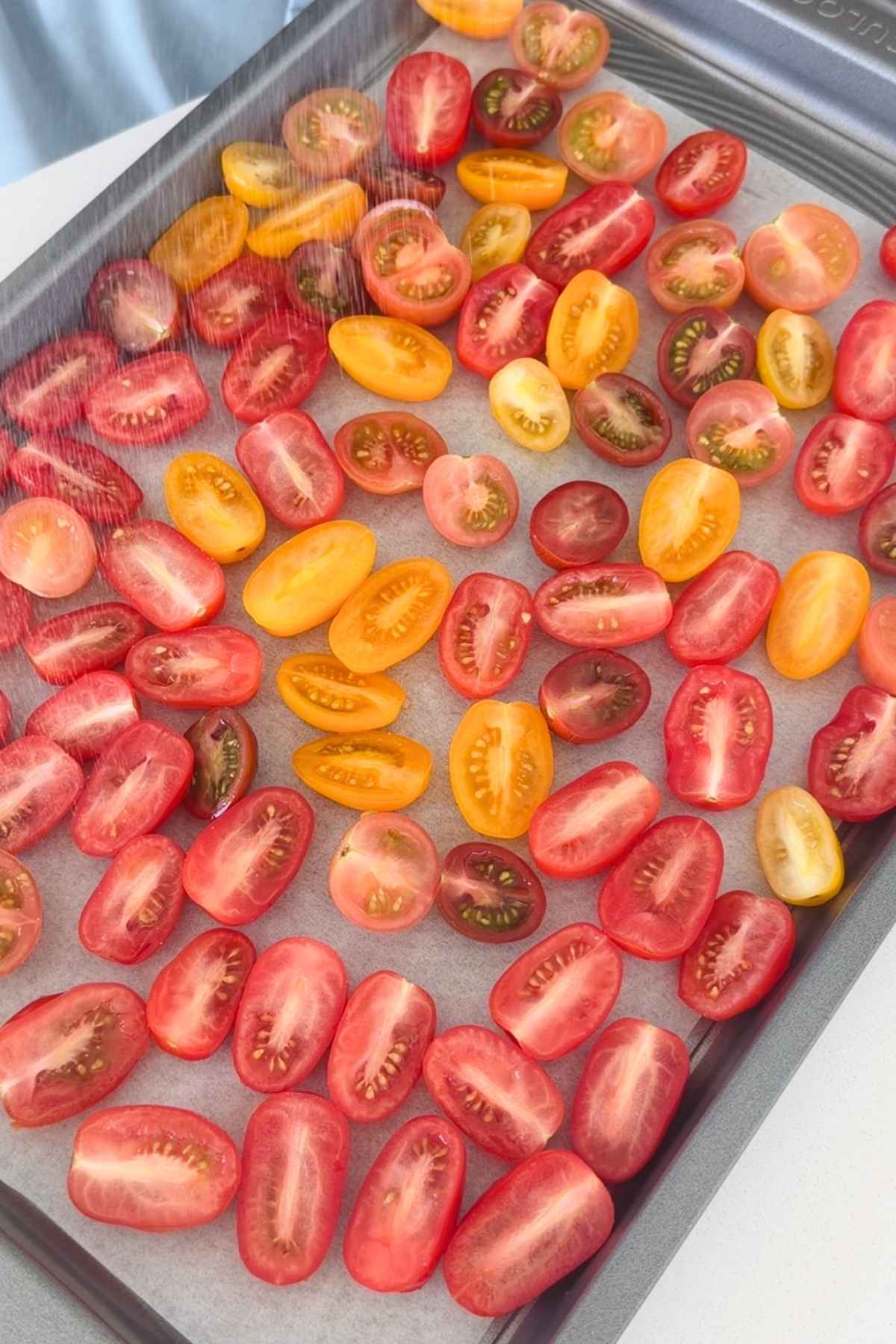 Halved cherry tomatoes on baking sheet.